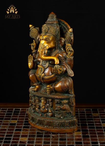 13" Lord Ganesh with Surya Halo seated on a pedestal with figurines of Ganesh and Lakshmi